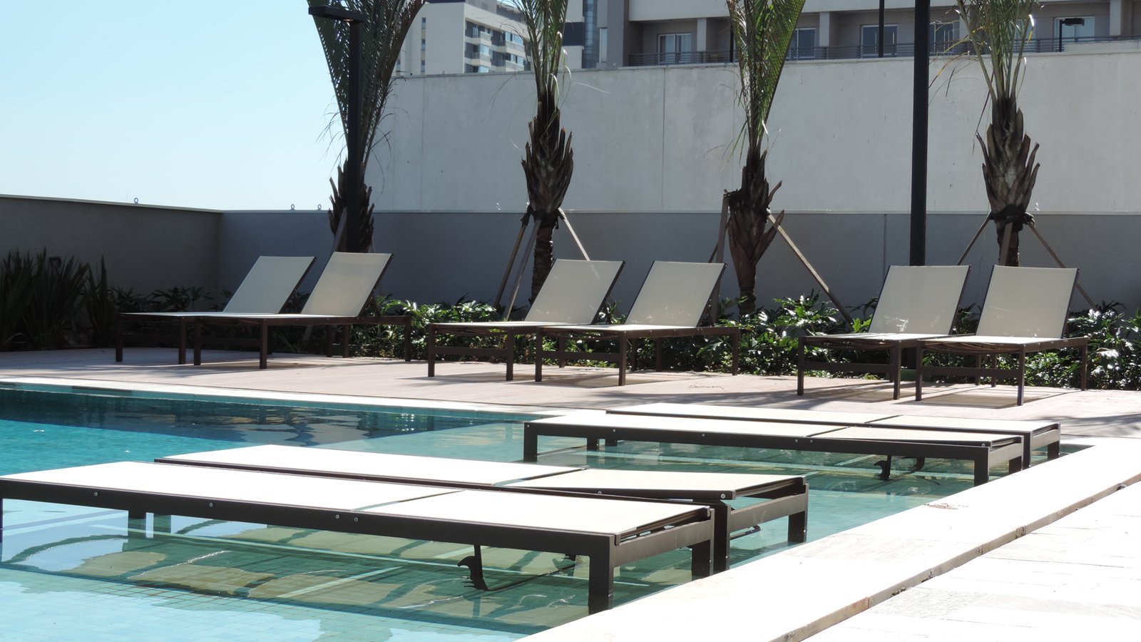 Espreguiçadeiras sling na borda e dentro da piscina