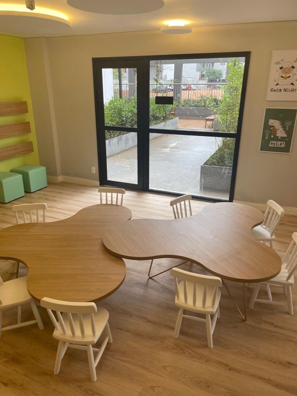Sala infantil com mesas orgânicas e cadeirinhas brancas